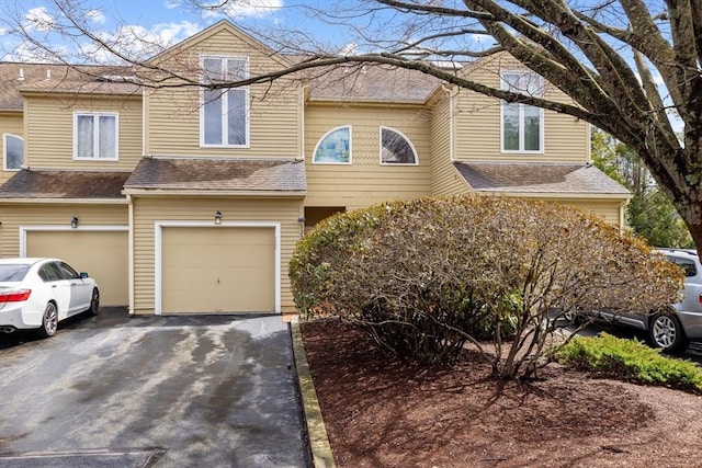 multi unit property featuring driveway, an attached garage, and a shingled roof