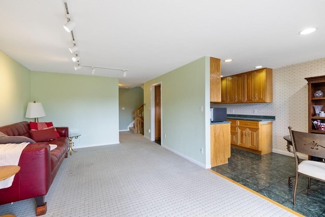 kitchen featuring open floor plan, baseboards, rail lighting, brown cabinets, and recessed lighting