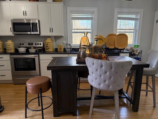 kitchen featuring light hardwood / wood-style floors, a healthy amount of sunlight, white cabinetry, and appliances with stainless steel finishes