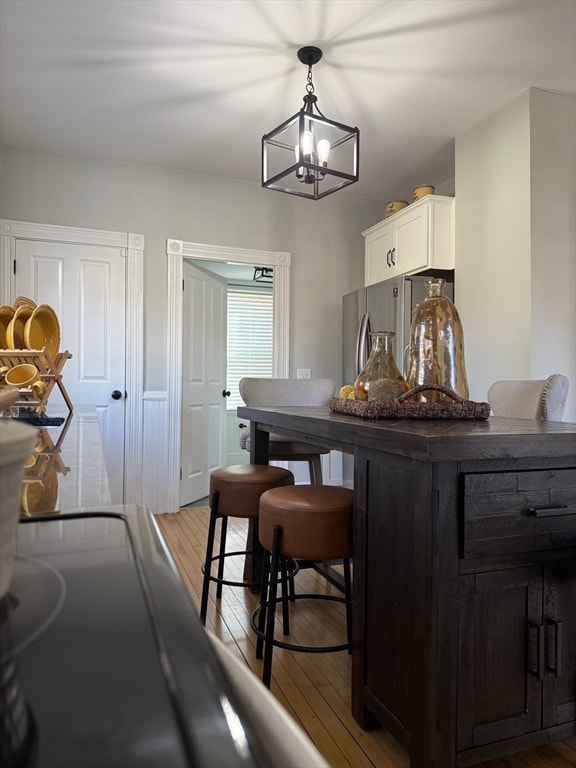 kitchen with white cabinets, light wood-type flooring, decorative light fixtures, and a notable chandelier