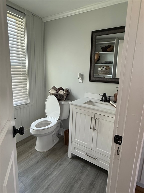 bathroom with ornamental molding, vanity, wood-type flooring, and toilet