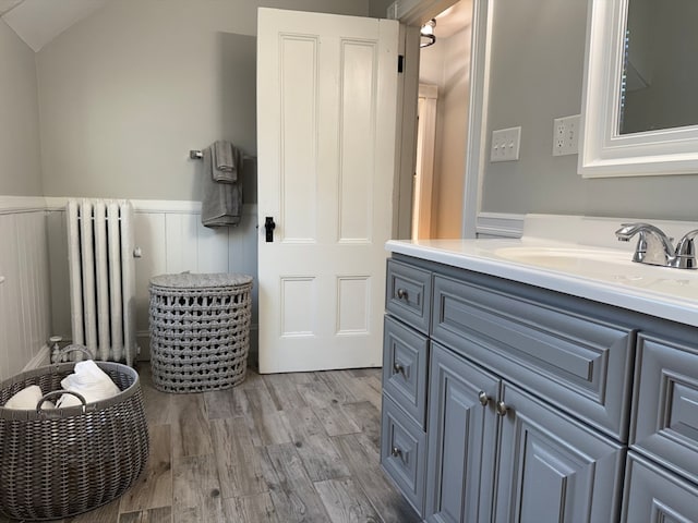 bathroom featuring radiator, vanity, wood-type flooring, and lofted ceiling