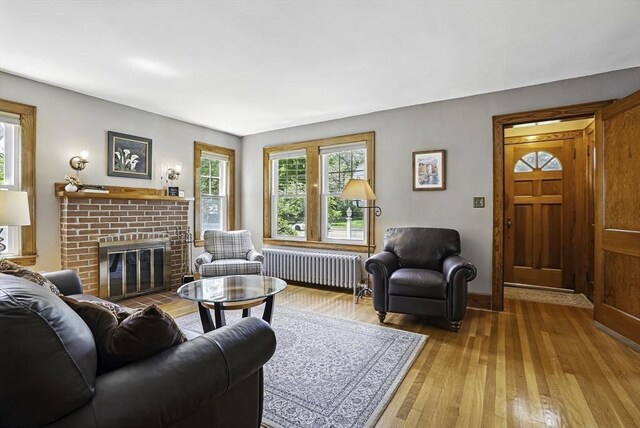 247 S St, Wrentham, MA 02093 - living area with radiator heating unit, wood-type flooring, a brick fireplace, and baseboards