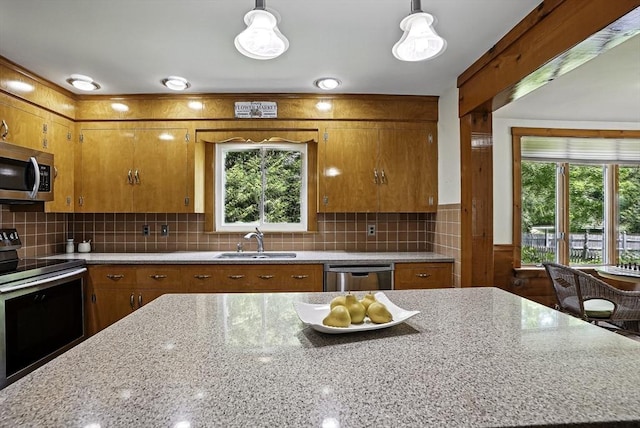 247 S St, Wrentham, MA 02093 - kitchen featuring appliances with stainless steel finishes, a sink, brown cabinetry, and light stone countertops