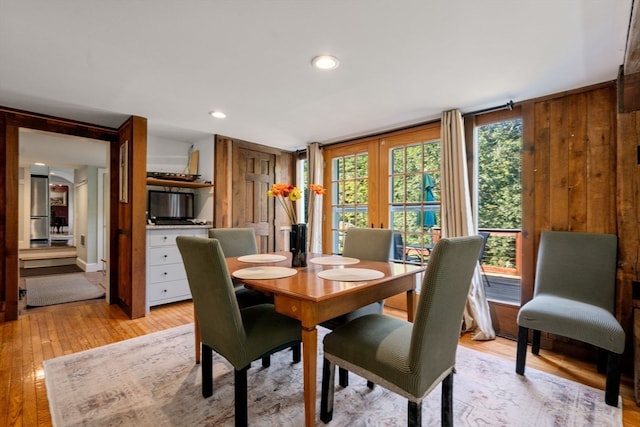 dining area with wood walls and light hardwood / wood-style floors