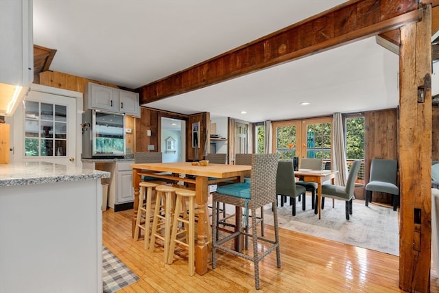 kitchen featuring white cabinets, light stone countertops, tasteful backsplash, and light hardwood / wood-style flooring