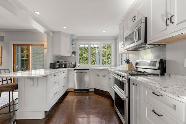 kitchen with ornamental molding, white cabinetry, stainless steel appliances, kitchen peninsula, and a breakfast bar