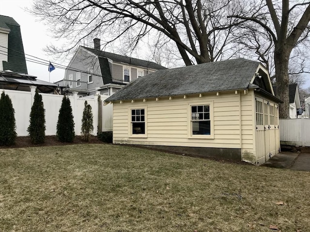 rear view of house featuring a lawn and an outdoor structure