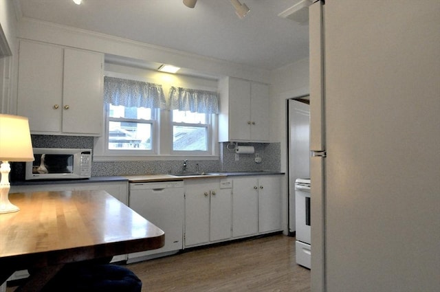 kitchen with decorative backsplash, light wood-type flooring, white appliances, sink, and white cabinets