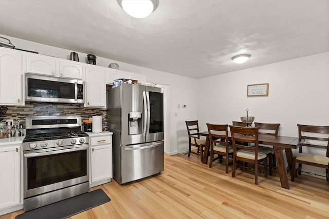 15 N St Unit 2, Haverhill, MA 01830 - kitchen with appliances with stainless steel finishes, white cabinetry, light wood-style floors, tasteful backsplash, and light countertops