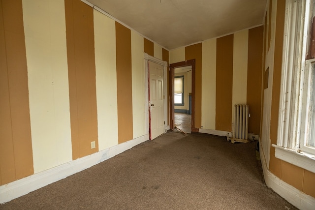 empty room featuring carpet flooring and radiator heating unit