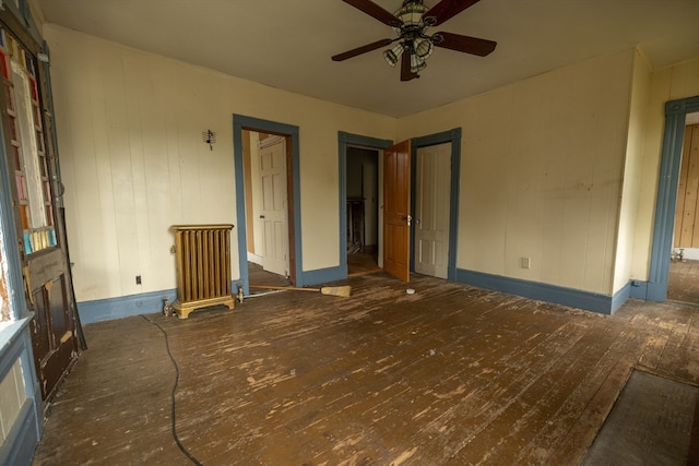 spare room featuring ceiling fan, wood walls, and dark hardwood / wood-style flooring