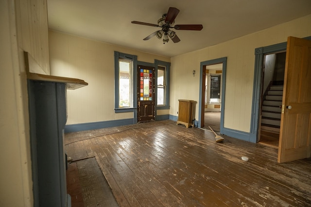 unfurnished living room featuring ceiling fan, dark wood-type flooring, and radiator heating unit