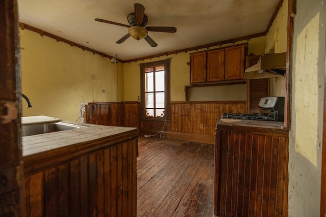 kitchen with ceiling fan, custom exhaust hood, stove, wood walls, and dark wood-type flooring