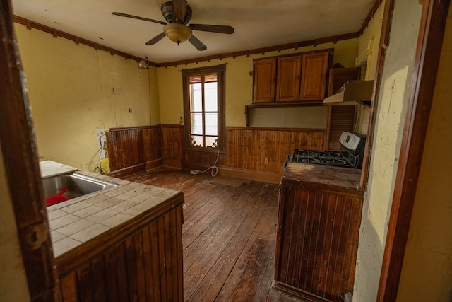 kitchen with stove, ceiling fan, sink, dark hardwood / wood-style flooring, and tile counters