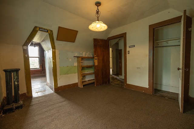 interior space featuring lofted ceiling and dark colored carpet