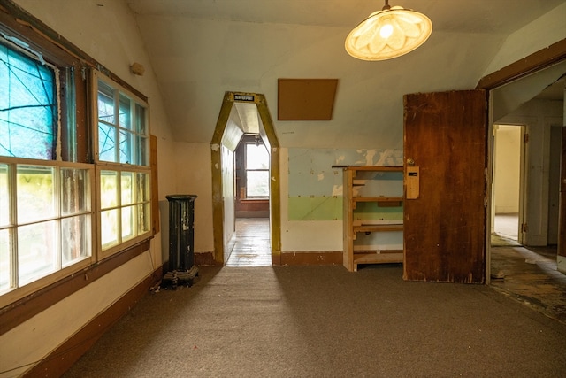 hallway with carpet flooring, vaulted ceiling, and a healthy amount of sunlight