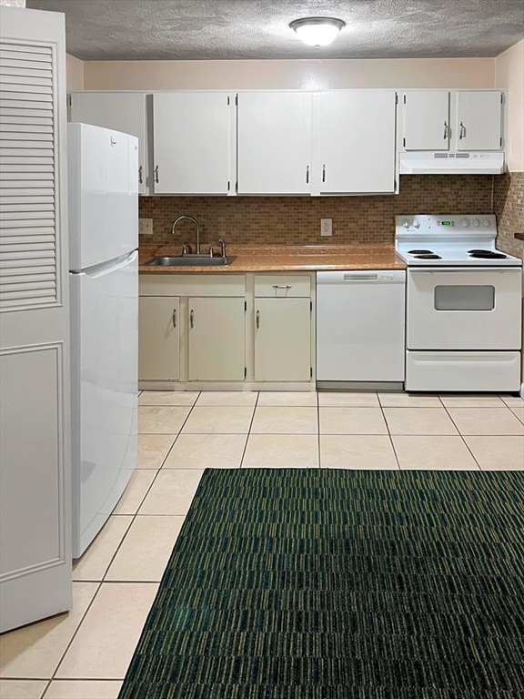 kitchen with light tile patterned flooring, sink, white appliances, white cabinets, and decorative backsplash