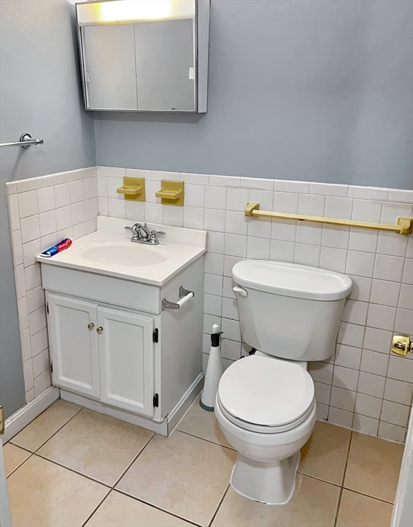 bathroom featuring tile patterned flooring, vanity, toilet, and tile walls