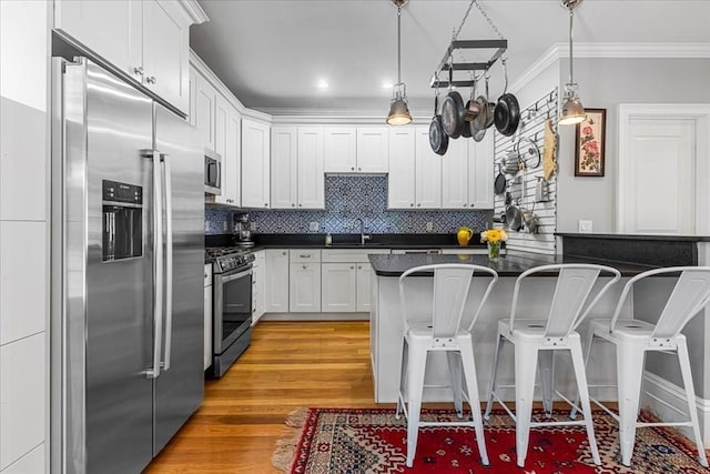 21 Hale St Unit 21, Newton, MA 02464 - kitchen with stainless steel appliances, dark countertops, a breakfast bar area, light wood-type flooring, and ornamental molding