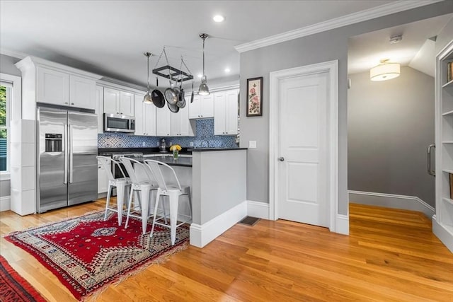 21 Hale St Unit 21, Newton, MA 02464 - kitchen with appliances with stainless steel finishes, dark countertops, a peninsula, light wood-style flooring, and white cabinetry