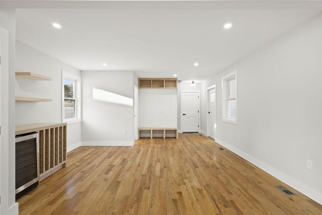 unfurnished living room with beverage cooler and light hardwood / wood-style flooring