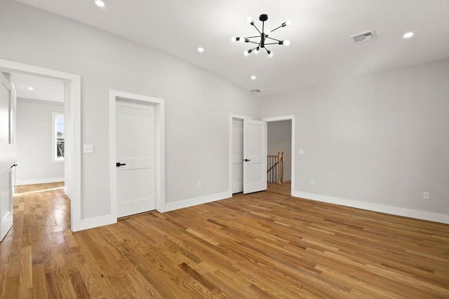 unfurnished bedroom featuring lofted ceiling, a notable chandelier, and light hardwood / wood-style flooring