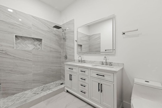 bathroom with toilet, a tile shower, and vanity