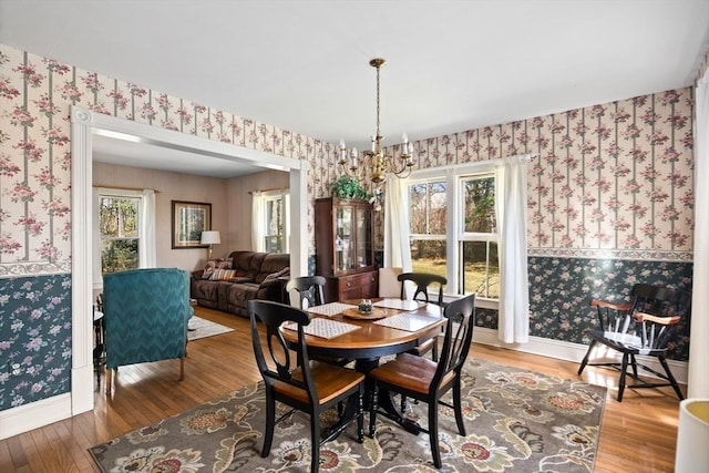 dining room featuring wallpapered walls, baseboards, hardwood / wood-style floors, and an inviting chandelier