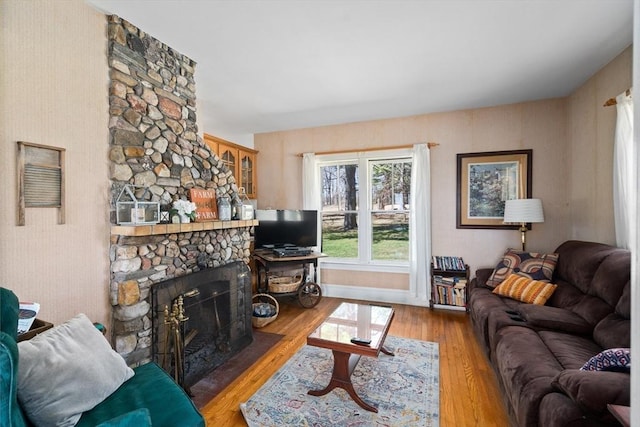 living room featuring wood finished floors and a stone fireplace
