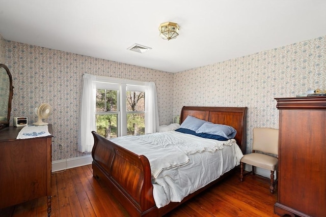 bedroom with baseboards, visible vents, wallpapered walls, and hardwood / wood-style flooring