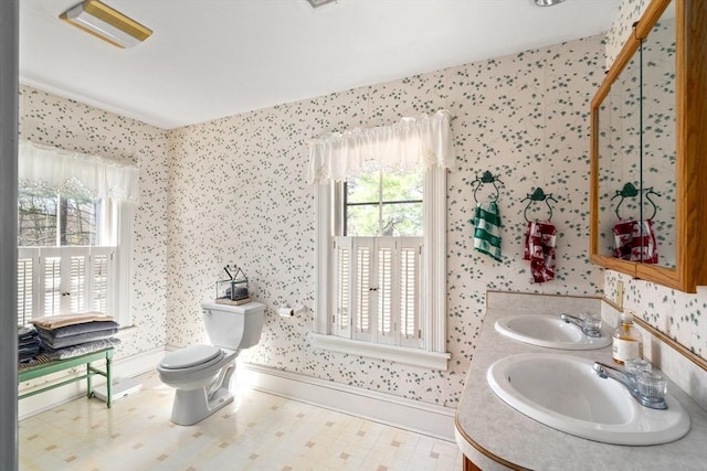 bathroom with a sink, toilet, a wealth of natural light, and wallpapered walls