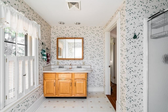 bathroom with a sink, wallpapered walls, and visible vents