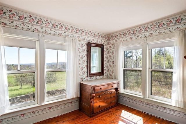 interior space with wallpapered walls, wood-type flooring, and a baseboard heating unit