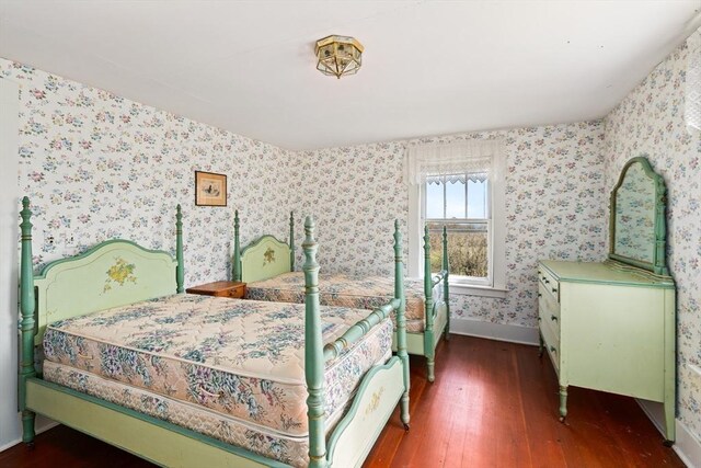 bedroom with wallpapered walls, baseboards, and hardwood / wood-style flooring