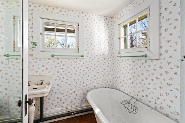 bathroom featuring a freestanding bath, a healthy amount of sunlight, and wallpapered walls