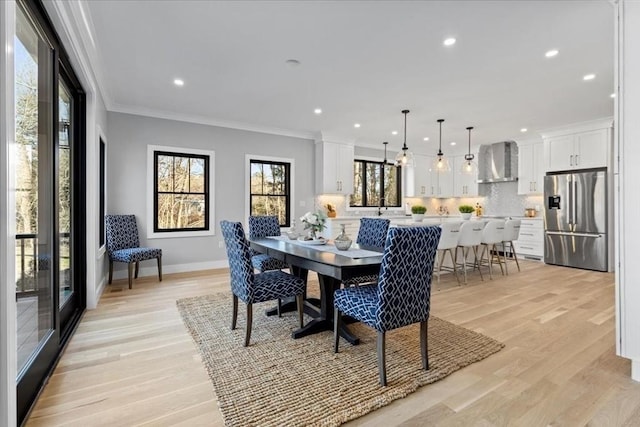 dining room featuring recessed lighting, baseboards, crown molding, and light wood finished floors