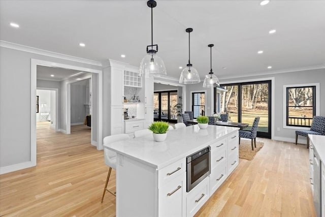 kitchen featuring light wood-type flooring, stainless steel microwave, recessed lighting, and white cabinetry