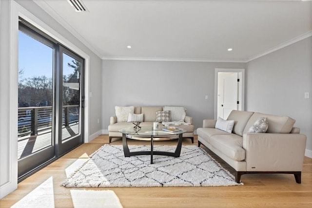 living area with visible vents, baseboards, wood finished floors, and ornamental molding