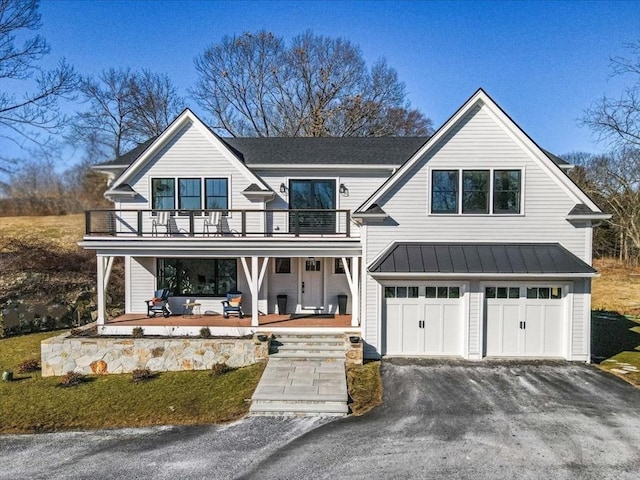 modern farmhouse style home with a balcony, driveway, a standing seam roof, a garage, and metal roof