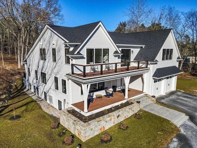 back of house with a yard, a shingled roof, a garage, a deck, and aphalt driveway