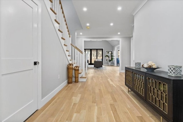 hallway with recessed lighting, light wood finished floors, baseboards, stairs, and vaulted ceiling