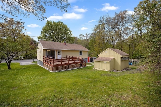 rear view of house featuring a storage unit, a wooden deck, a yard, and an outdoor structure