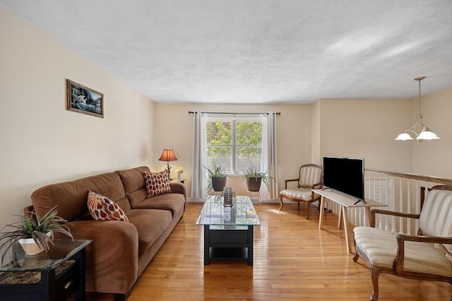 living room with light wood finished floors, a chandelier, and a textured ceiling