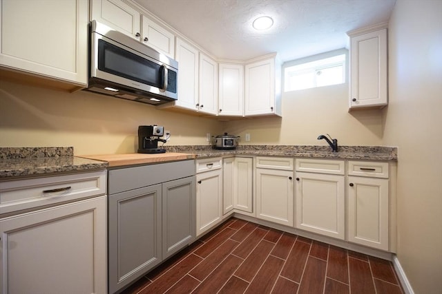 22 Hartley Ave, Brockton, MA 02302 - kitchen featuring stainless steel microwave, dark wood-style flooring, white cabinets, and light stone countertops