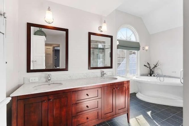 bathroom with lofted ceiling, a tub to relax in, tile patterned flooring, and vanity