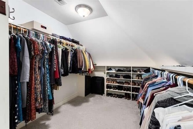 spacious closet with lofted ceiling and light colored carpet