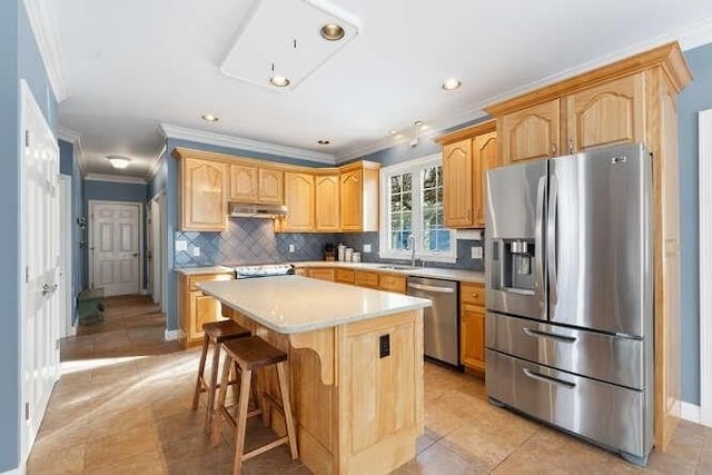 kitchen featuring a kitchen island, appliances with stainless steel finishes, tasteful backsplash, sink, and a kitchen bar