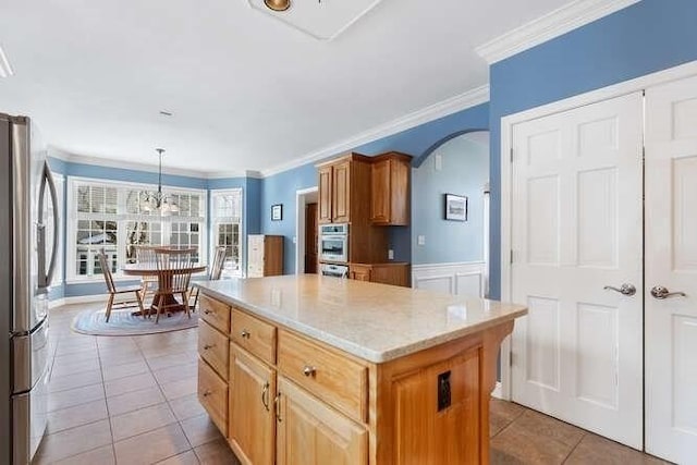 kitchen featuring a kitchen island, appliances with stainless steel finishes, decorative light fixtures, light tile patterned floors, and crown molding