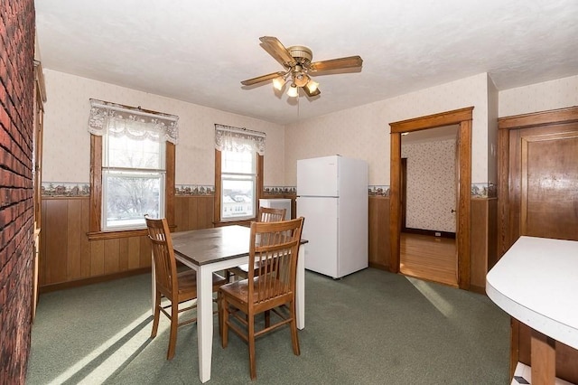 dining space featuring ceiling fan and dark colored carpet